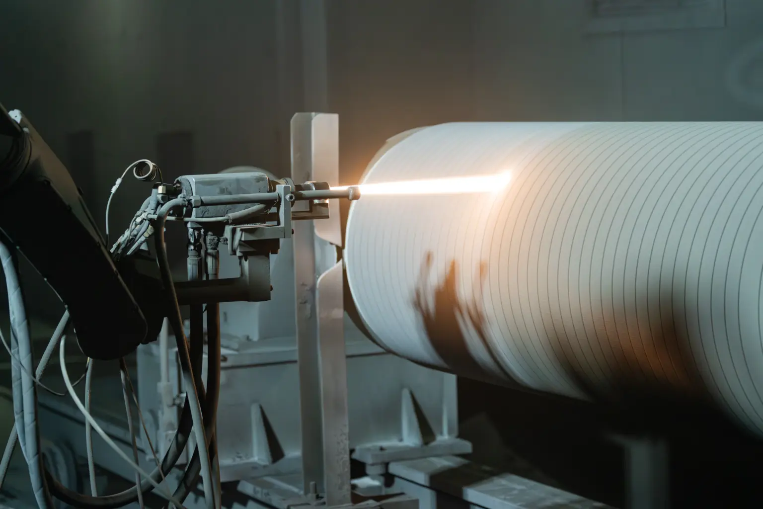 Technician performing tungsten carbide spraying on a corrugating roll surface for enhanced wear resistance and extended roll life.
