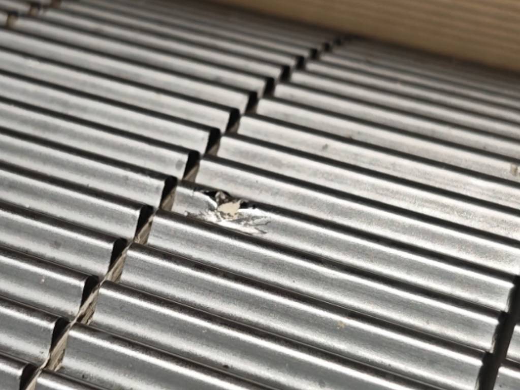 Close-up photo of a corrugating roll with chipped flute tips, a common surface damage that requires roll replacement.