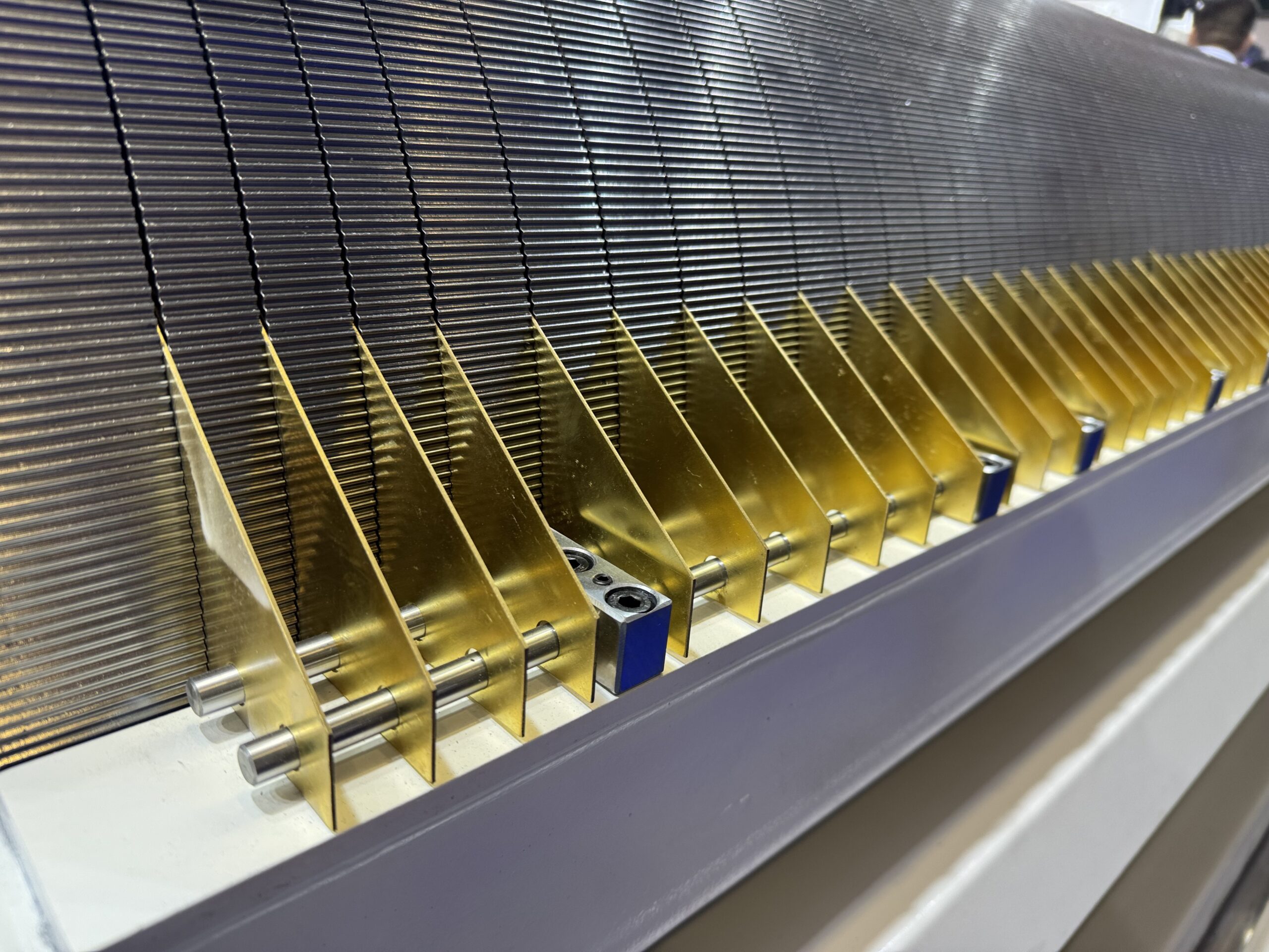 A technician using a feeler gauge to measure the gap between two large industrial rolls