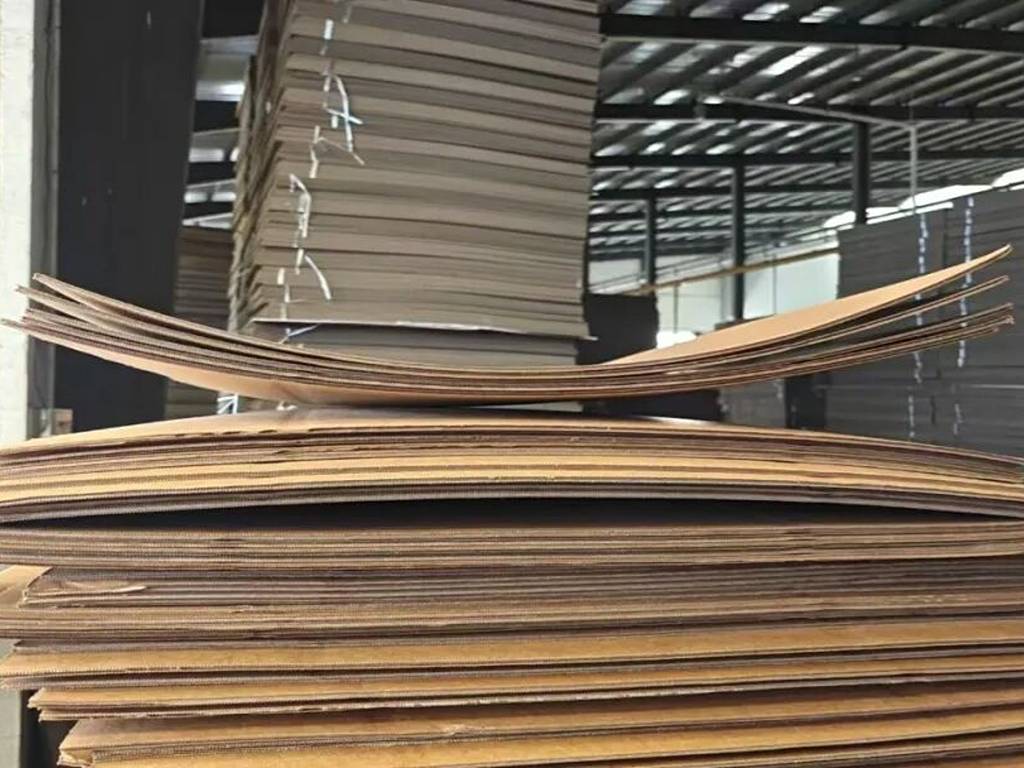 Warped corrugated board caused by moisture imbalance, uneven web tension, or improper machine settings during corrugated board production.